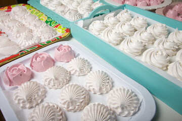 Homemade marshmallows of various shapes and colors are laid out on trays. Stabilization of Zephyr before packaging.