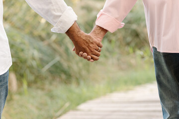 Happy male gay couple holding hands while enjoying a walk together in nature. LGBT couple concept.