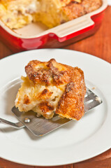 top view, close distance of a section of pear, raisin cobbler, on a spatula, and setting on a white, round plate with heat resistant bowl filled with rest of cobbler