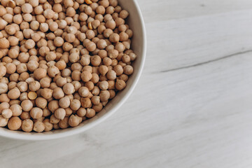 View from above. A plate with raw chickpeas on a white table. Healthy food concept