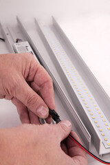The man works with a drill. Installation of a diode lamp. Construction concept. 