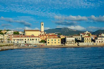 Fototapeta na wymiar Panorama of the city of San Vincenzo, seen from the sea. Blue sky and clouds. Livorno, Tuscany, Italy