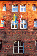 Facade of an old, traditional, silesian brick block house in Nikiszowiec, Katowice, Poland. Polish and Silesian flag hanging outside the building.