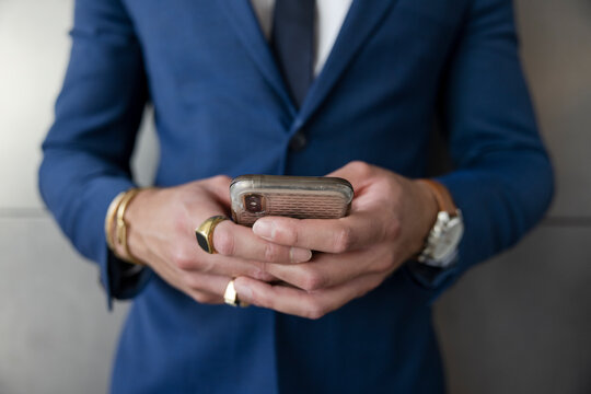 Close up businessman in suit and rings using smart phone