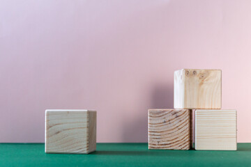 wooden cubes still life against pale pink and emerald green background