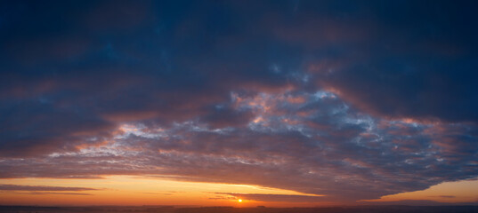 Dramatic sunset, the sun's rays shine through the clouds.