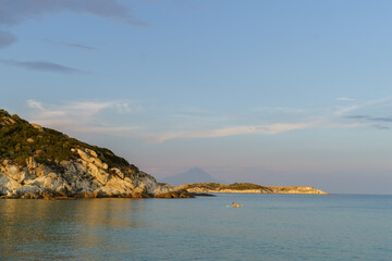Sea mountain view with man surfing on sup board on sunny day. High quality photo