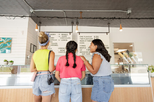 Rear view of girlfriends looking at menu in gelato shop