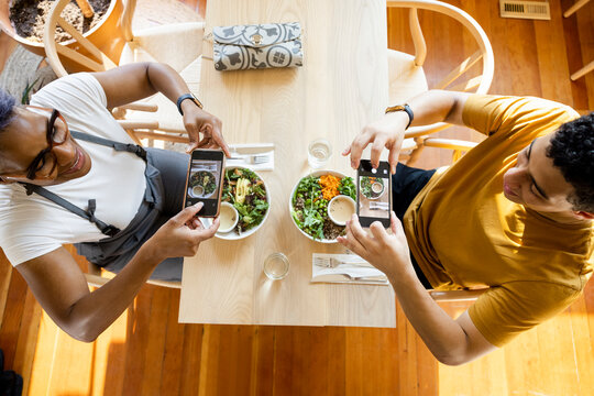 Overhead view of customers taking photograph of food in cafe