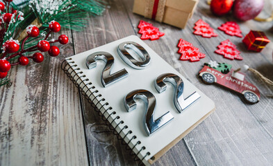 numbers 2022 on a spiral notepad on a wooden background with Christmas decorations 