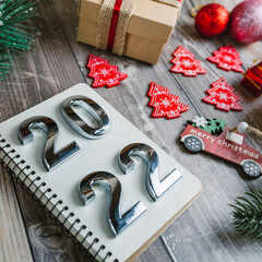 numbers 2022 on a spiral notepad on a wooden background with Christmas decorations 