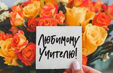 bright bouquet of orange yellow roses and white cardboard card with the inscription for beloved teacher on russian, teachers day holiday concept