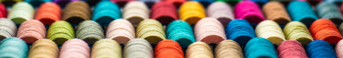 Multi-colored sewing threads laid out in a row. Bright background.