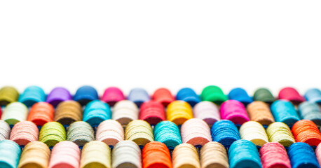 Multi-colored sewing threads laid out in a row. Bright background.