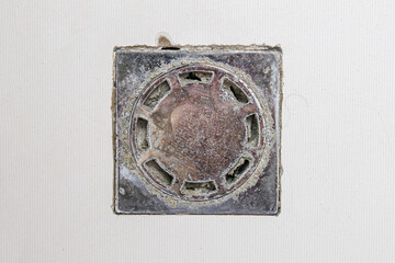 Dirty clogged square metal drain hole in a shower, bathroom needed to be cleaned and purged