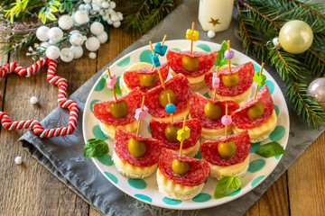 Festive snack of canapes on the Christmas table. Canapes with bread, cheese, salami and olives.