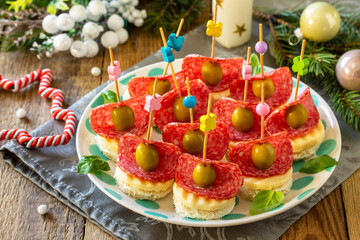 Festive snack of canapes on the Christmas table. Canapes with bread, cheese, salami and olives.