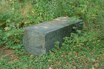 Fototapeta premium one black gray dirty big granite block lies in green grass outside