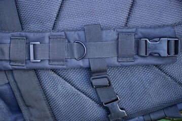 one large black fabric harness with metal rings and plastic carabiners on a tactical backpack