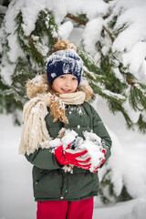 Happy child girl plaing with snow on a snowy winter walk