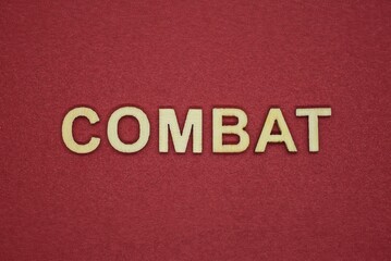 Fototapeta na wymiar text the word combat from gray wooden small letters on an red table