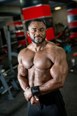 Fototapeta na wymiar Bodybuilder is posing. Beautiful sporty guy male power. Fitness muscled man without shirt on dark gym background