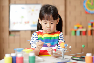 young girl painting swivelling solar system toy at home