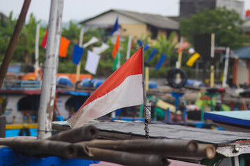 Indonesia red white flag fluttering on a fishing boat with defocused background at Pelabuhanratu Sukabumi Seaport, West Java, Indonesia.