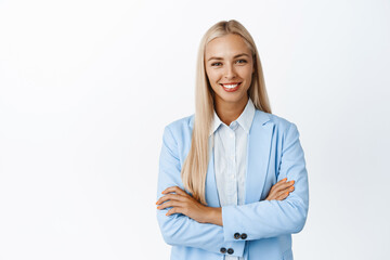 Ambitous young corporate woman in suit, cross arms on chest, smiling and looking confident,...