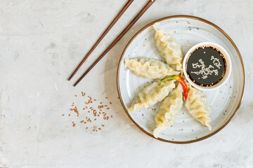 Japanese or Chinese national dish, gyoza dumplings with meat, seafood or vegetables. Top view On a gray stone background with chopsticks and soy sauce. Space for text