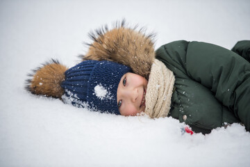 Happy child girl plaing with snow on a snowy winter walk