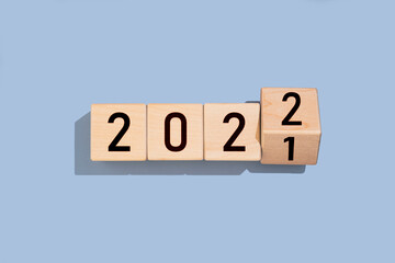 Wooden cube with the number 2021 to 2022 on blue background. Happy new year.