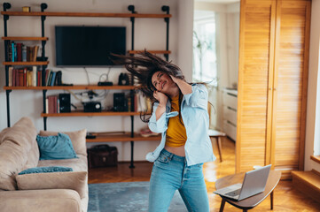Woman dancing at home while listening music on a headphones