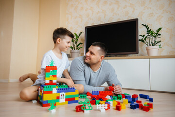 A little boy together with his father is played by a constructor and builds a house. Construction of a family home.