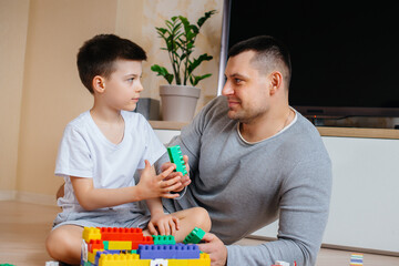 A little boy together with his father is played by a constructor and builds a house. Construction of a family home.