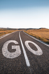 Go word written on highway road in the middle of empty asphalt road in beautiful blue sky