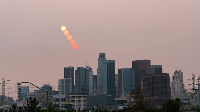 Time lapse day to night transition of red sun over Los Angeles skyline obscured by smoke from KNP Complex wildfire in California in 2021