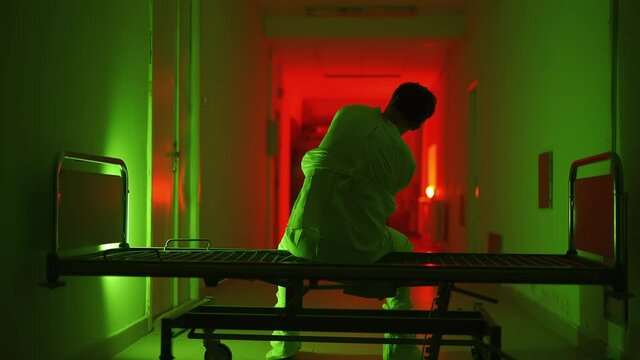 A mad male patient in straitjacket is going crazy in a mental hospital. Mentally ill man with psychic disorders and bipolar disease. Concept of paranoia or schizophrenia and madness or depression.