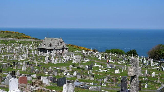 Slow panning shot of Welsh cemetery on the Great Orme hill by the sea in Llandudno seaside town.