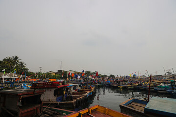 Indonesian Fishing boats with grey cloudy sky leaning on the Pelabuhan Ratu Sukabumi port