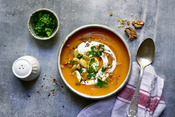 Delicious autumn pumpkin soup with cream and walnuts. Top view with copy space.