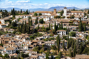 Beautiful panorama of the Albaicín, the historic city center of Granada with its characteristic white house under a picturesque cloudy blue sky, seen from the Alhambra palace, Andalusia, Spain - obrazy, fototapety, plakaty