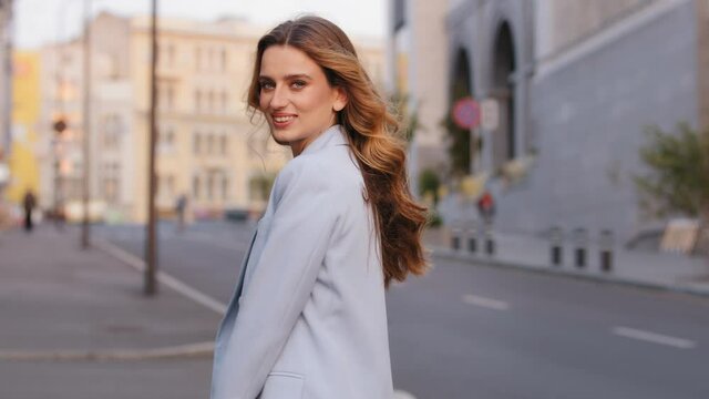Young stylish beautiful attractive business woman in trendy blue suit posing in city looking at camera. Pretty carefree caucasian 20s 30s lady girl model student whirling in street outside outdoors