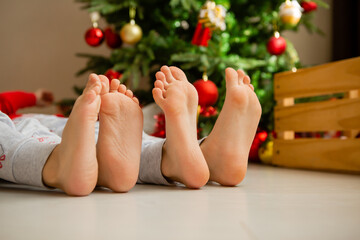 closeup of the bare feet of two children sitting on the floor near the Christmas tree. winter New Year's concept. space for the text. High quality photo