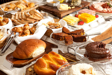 Mesa com pães, bolos e queijos. Típico buffet de café da manhã de hotel.