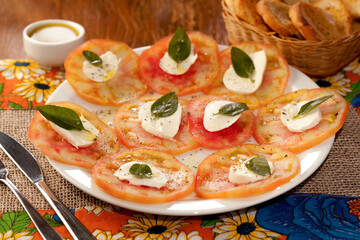 Carpaccio de tomate com queijo de búfala e folhas de manjericão temperados com azeite e pimenta preta.