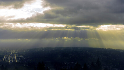 Dramatic sunlight shining through dark clouds over Fraser Valley and Port Moody, BC.