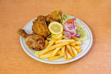 Menu plate with pieces of broaster chicken in batter with salad guarnicion with purple onion with...