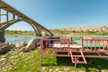 Metallic structure with mats and cushions to have a relaxing time on the banks of the Tigris river and in the shadow of a bridge with two arches