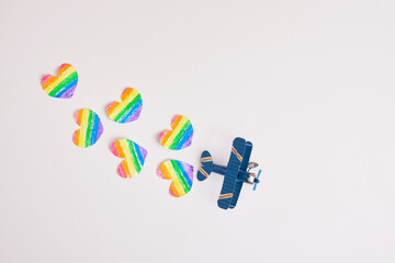 toy airplane and paper drawn cut out hearts rainbow colors on gray background